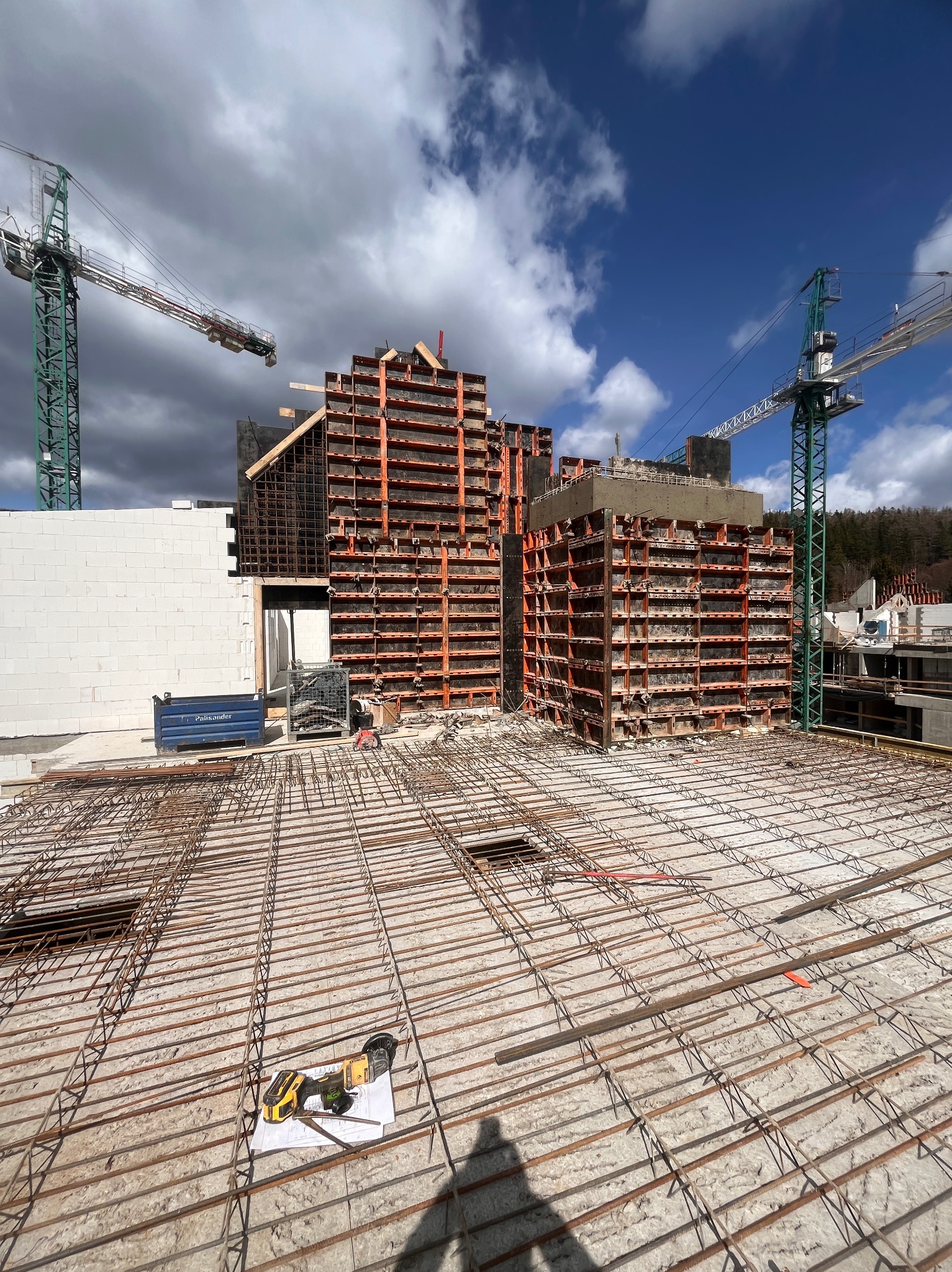 Zbrojenie płyty stropowej na budowie w Legnicy, widoczne szalunki ścian i żurawie budowlane na tle pochmurnego nieba.