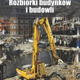Żółta koparka na tle zrujnowanego budynku w trakcie rozbiórki, widoczne fragmenty ścian i gruzowisko, w tle budynki miejskie.