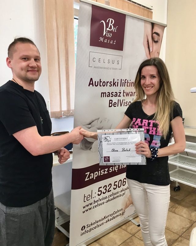 Wręczenie certyfikatu za lifting twarzy BelViso. Uścisk dłoni, uśmiechnięta kobieta z certyfikatem na tle rollupu z logo i danymi kontaktowymi Celsus Akademia Masażu.