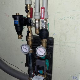 WAGREX bis Sebastian Piątkowski - Fragment instalacji hydraulicznej z manometrami, filtrem Caleffi, zaworami Calido i pompą obiegową Wilo-Yonos Pico plus, zamontowanej na ścianie z odręcznymi notatkami.