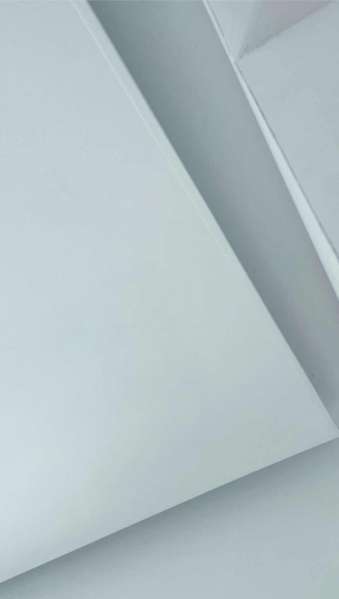 Fragment konstrukcji sufitu podwieszanego z płyt gipsowo-kartonowych, widoczne łączenie płyt pod kątem, oświetlone z góry.