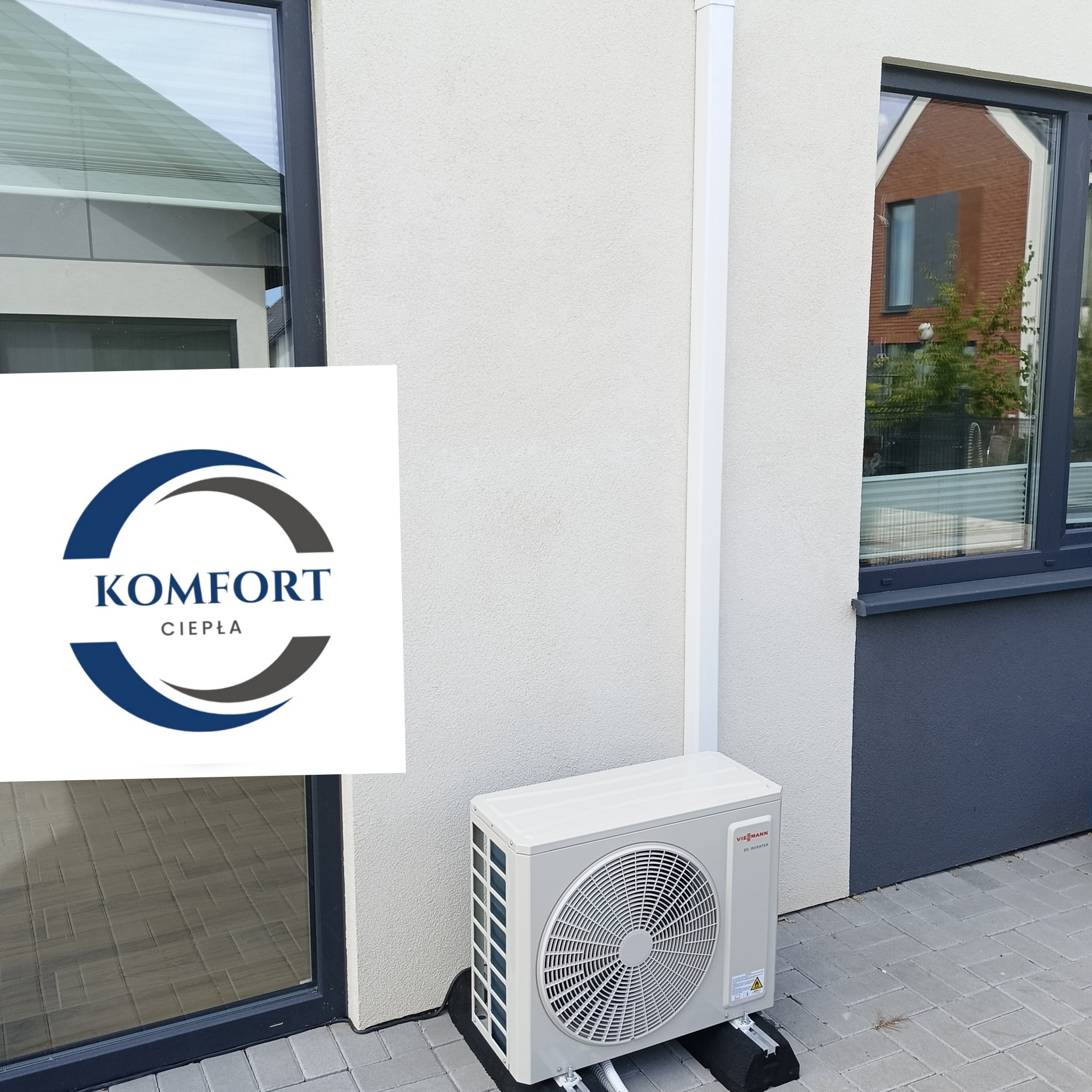 Zewnętrzna jednostka klimatyzacji Viessmann zamontowana przy ścianie budynku, z widocznym logo firmy Komfort Ciepła w lewym górnym rogu.