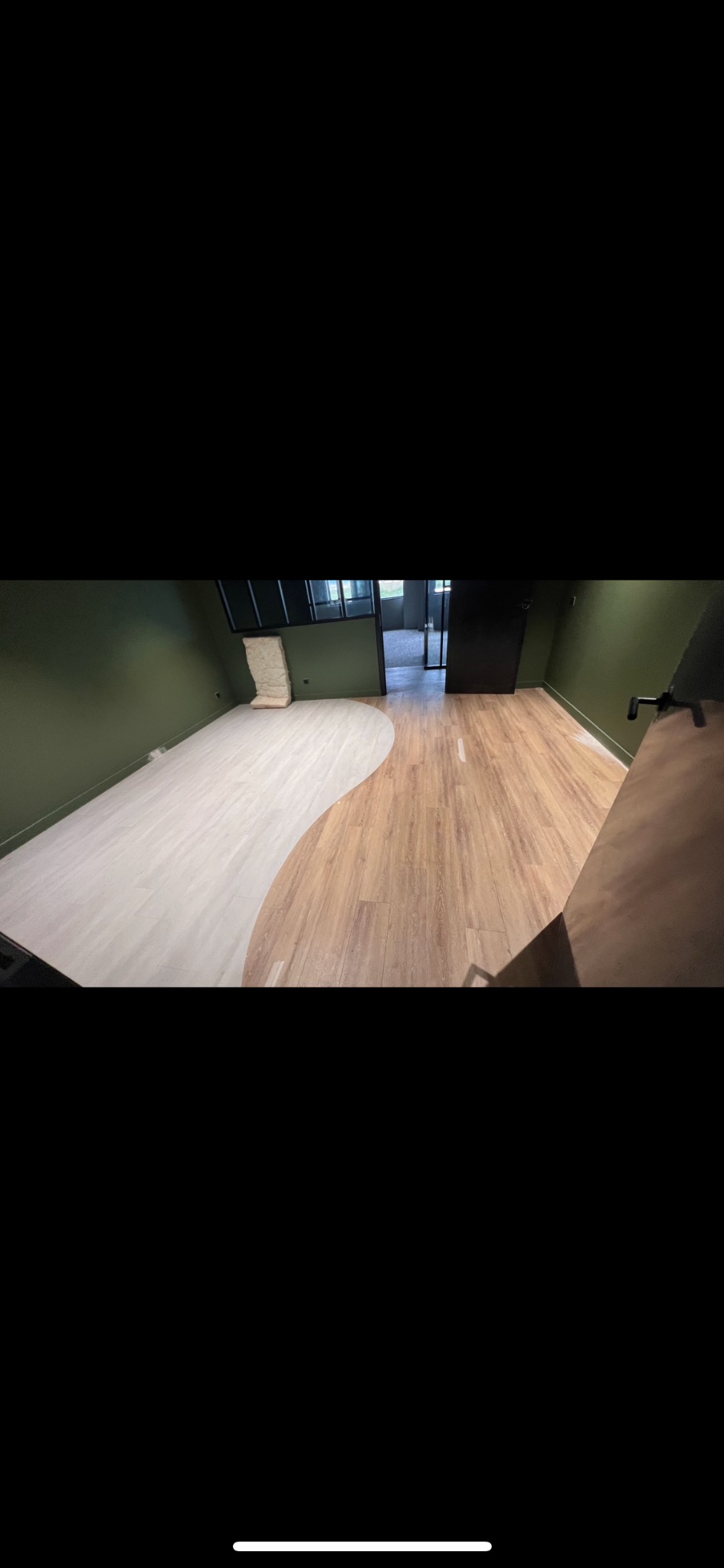 Nowoczesne ułożenie paneli w kształcie fali, łączące dwa odcienie drewna w Ręczno. Nietypowe wzornictwo podłogi w zielonym pomieszczeniu.