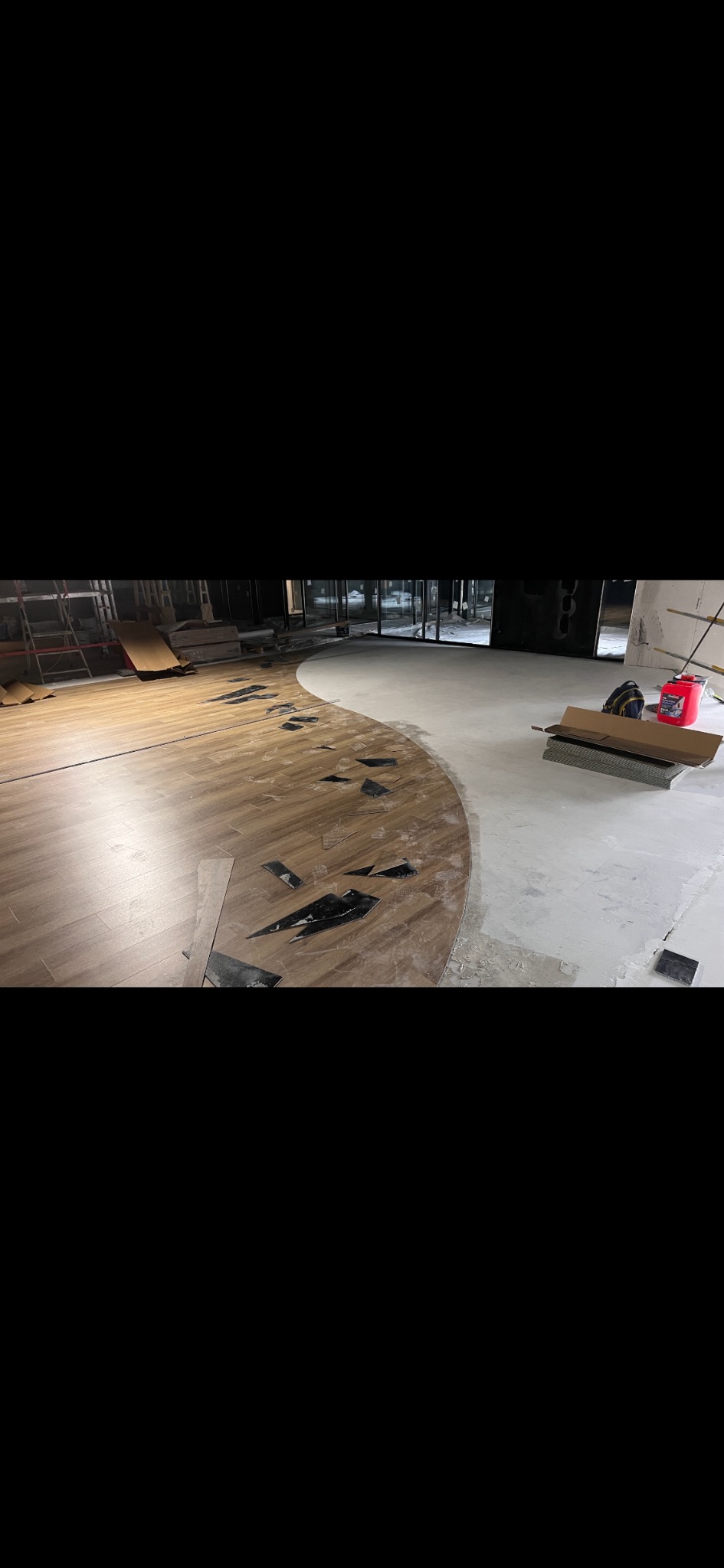 Układanie podłogi z paneli w kształcie fali. Część podłogi wyłożona, widoczne narzędzia i resztki materiałów. Jasne, naturalne światło.