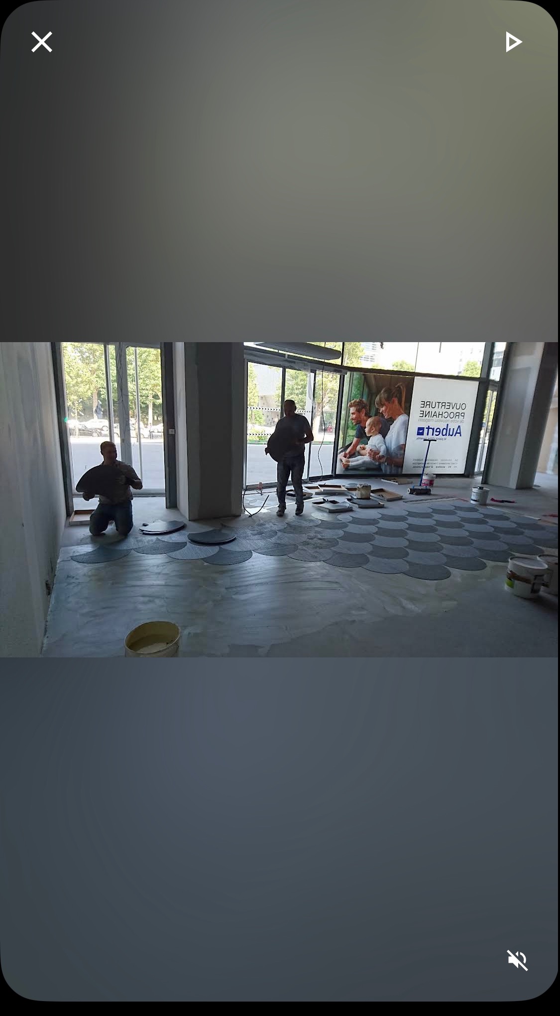 Układanie podłogi z okrągłych płytek w lokalu usługowym. Dwóch pracowników w trakcie pracy, widoczne narzędzia i częściowo ułożona podłoga.