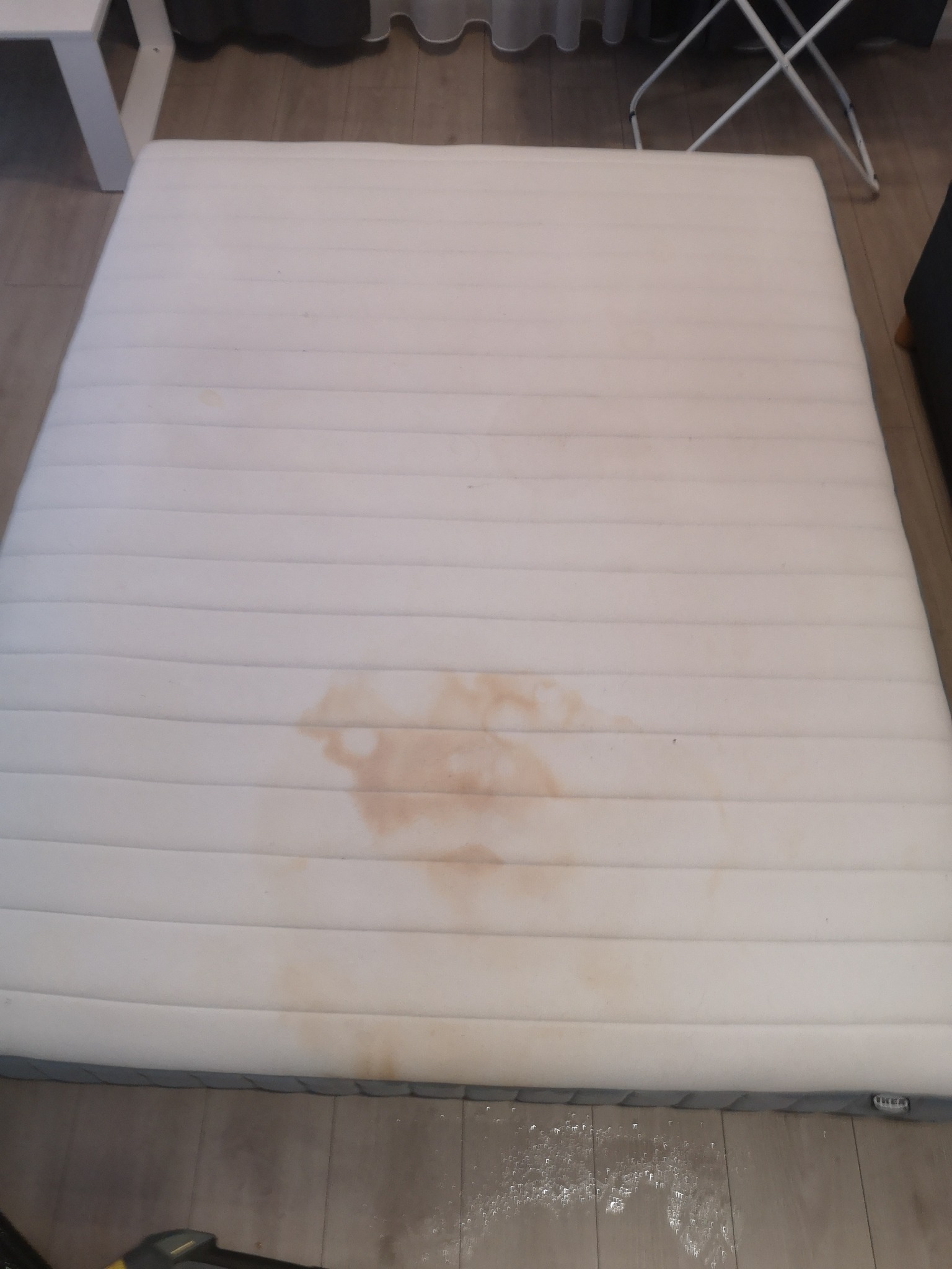 Biały materac z widocznymi, brązowymi plamami, wymagający prania w Dąbrowie.