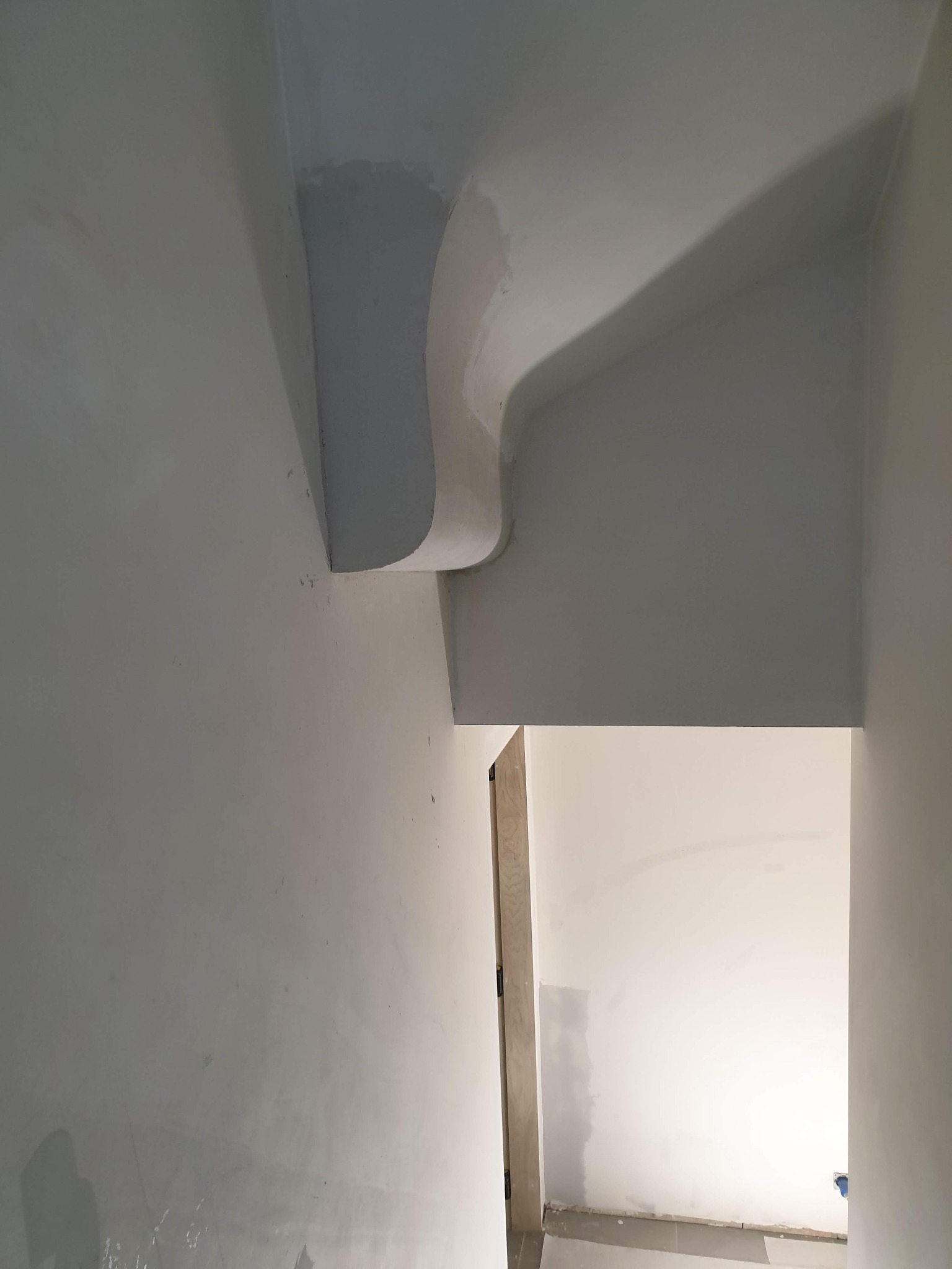 Wnętrze w trakcie prac wykończeniowych, widoczne fragmenty ścian i sufitu z elementami dekoracyjnymi w postaci łuków, ślady świeżo nałożonej gładzi.