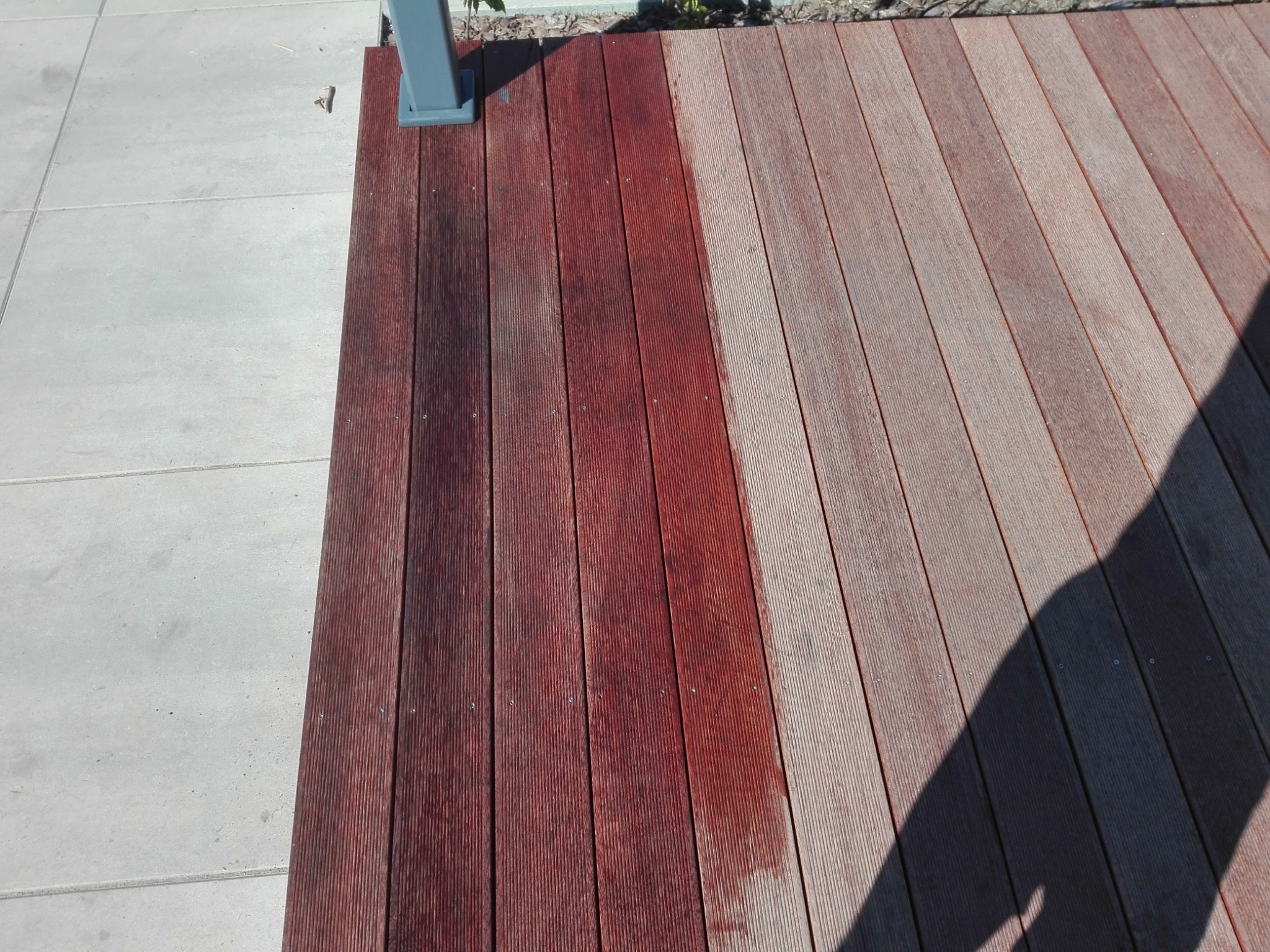 Częściowo odnowiony taras drewniany z widocznym fragmentem szarej betonowej nawierzchni i słupka konstrukcyjnego