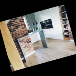 Nowoczesna biała kuchnia z ceglanym barem i drewnianą podłogą, oświetlona wiszącymi lampami, z widocznymi półkami i sprzętem AGD.