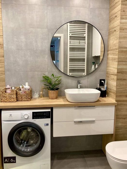 Nowoczesna łazienka z pralką Electrolux, białą umywalką nablatową, okrągłym lustrem z czarną ramą i grzejnikiem drabinkowym.