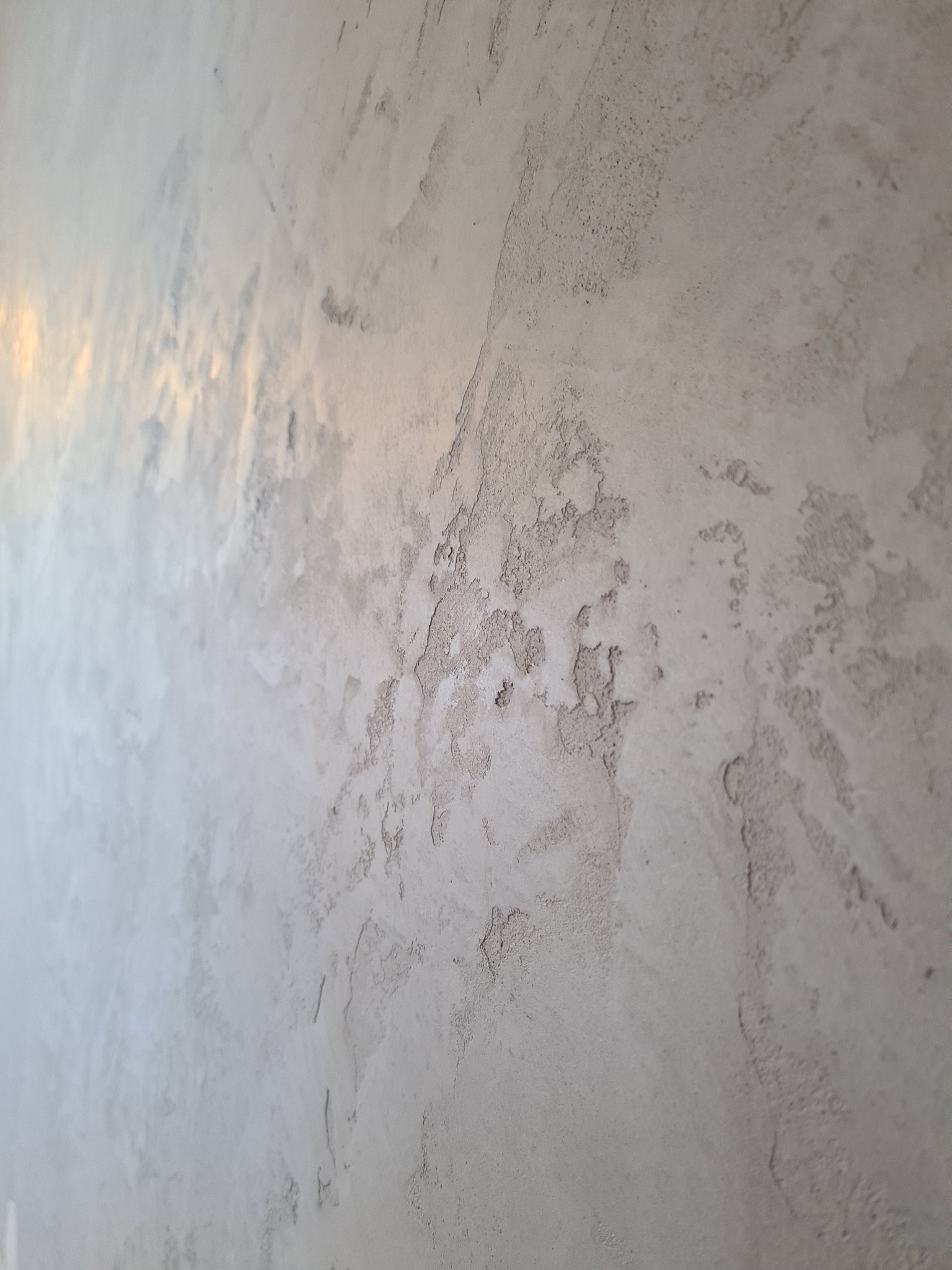 Ściana z szarą, dekoracyjną fakturą w stylu betonu architektonicznego, z delikatnym połyskiem i nierównomierną strukturą.