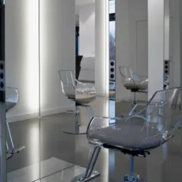 Nowoczesne stanowiska fryzjerskie z lustrami w minimalistycznym salonie, transparentne krzesła fryzjerskie z chromowanymi podstawami, pionowe oświetlenie LED.