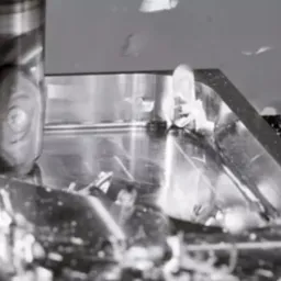 Frezarka CNC w trakcie obróbki metalowego elementu, wióry w powietrzu, widoczne detale frezu i obrabianego przedmiotu.