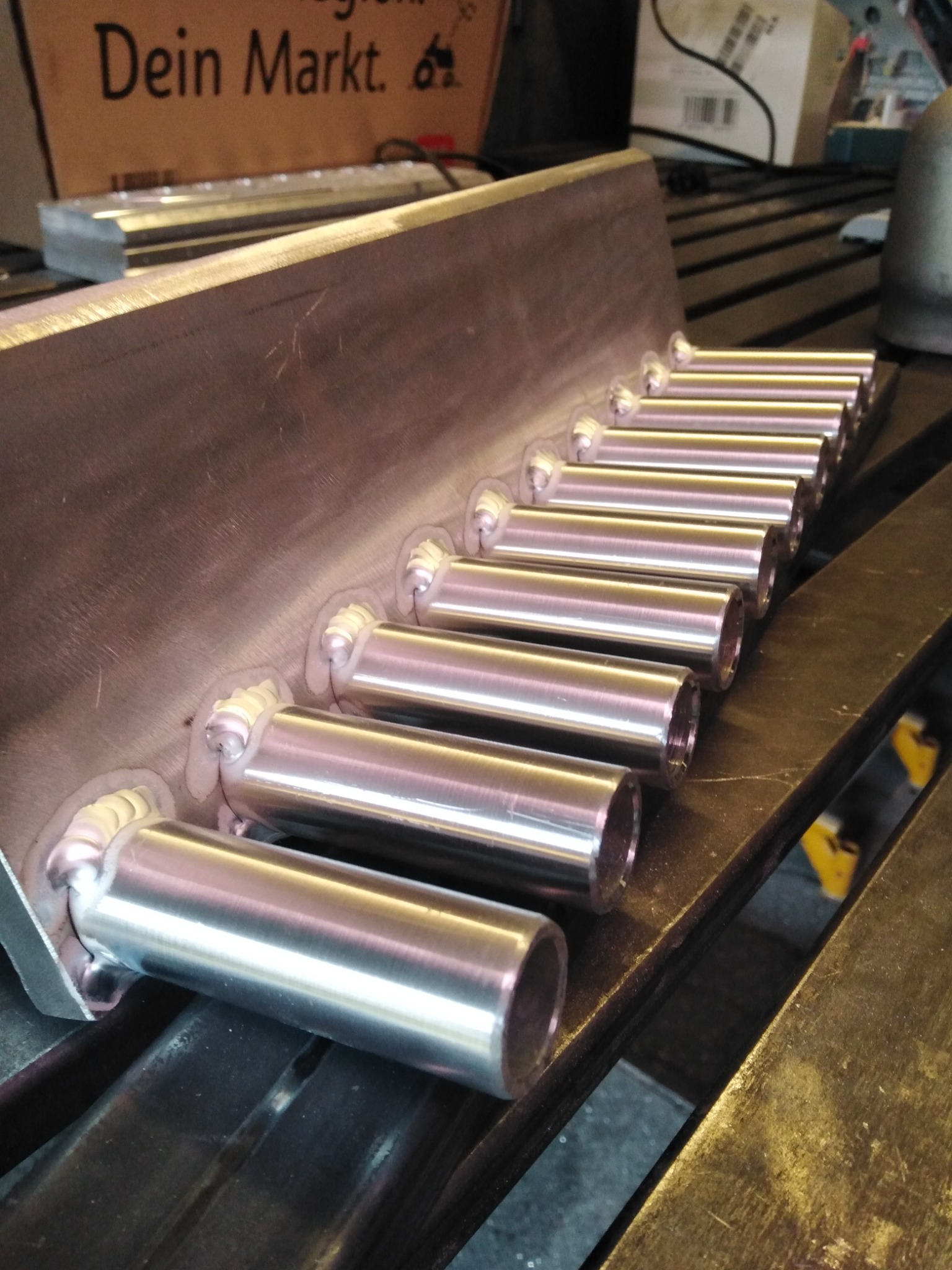 Metalowa konstrukcja z przyspawanymi rurami, widoczne spoiny i obróbka metalu na warsztatowym stole.