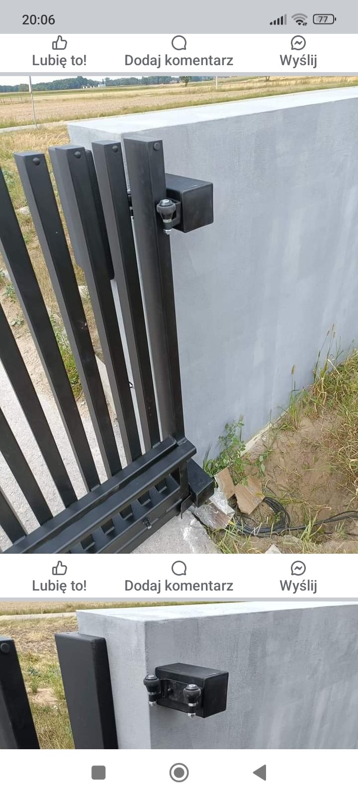 Fragment czarnej, przesuwnej bramy z widocznym mechanizmem jezdnym na betonowym słupku, w tle pole uprawne.