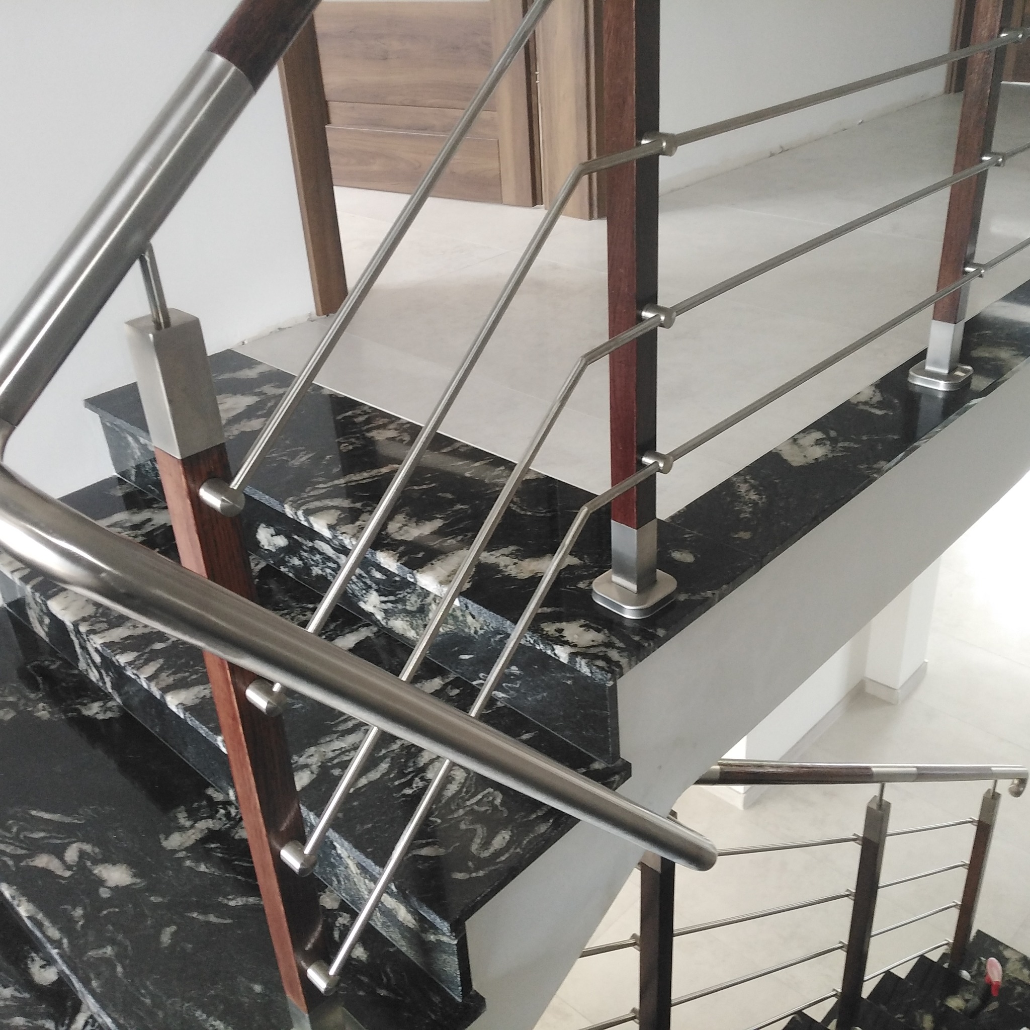 Schody z czarnego marmuru z balustradą ze stali nierdzewnej i drewnianymi słupkami, widok z góry, nowoczesny design.