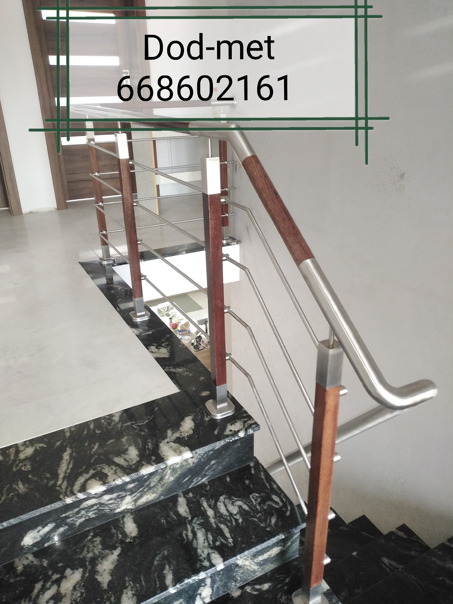 Schody z balustradą ze stali nierdzewnej z drewnianymi elementami, widok z góry na marmurowe stopnie, w tle widoczne pomieszczenie z drzwiami i numer telefonu firmy Dod-met 668602161.