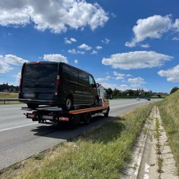 PROMAR Pomoc Drogowa Opole 24h Autostrada A4 Opolskie - Czarny Opel Vivaro na lawecie pomocy drogowej, widok z tyłu na autostradzie w słoneczny dzień.