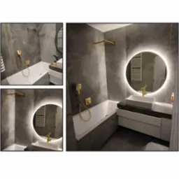 Nowoczesna łazienka z szarymi płytkami imitującymi marmur, złotą armaturą i okrągłym lustrem z podświetleniem LED. Widoczna wanna, umywalka nablatowa i grzejnik drabinkowy. Na blacie leży wiertarka.