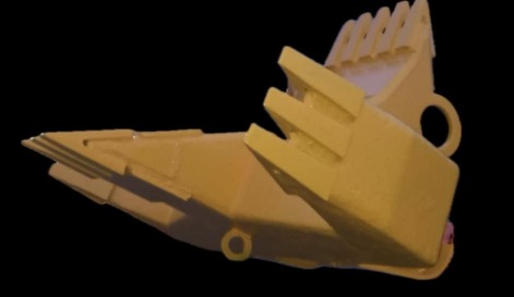 Żółty osprzęt do maszyny budowlanej na czarnym tle. Widoczne zęby i mocowania, sugerujące zastosowanie w koparce lub innym sprzęcie do robót ziemnych.