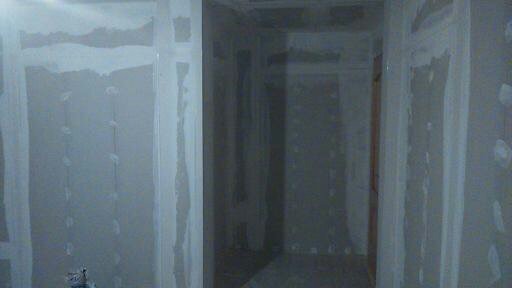 Ściany w trakcie przygotowania do dalszych prac wykończeniowych, widoczne ślady po szpachlowaniu i wzmocnienia narożników, surowy stan wnętrza z widocznymi otworami po kołkach.