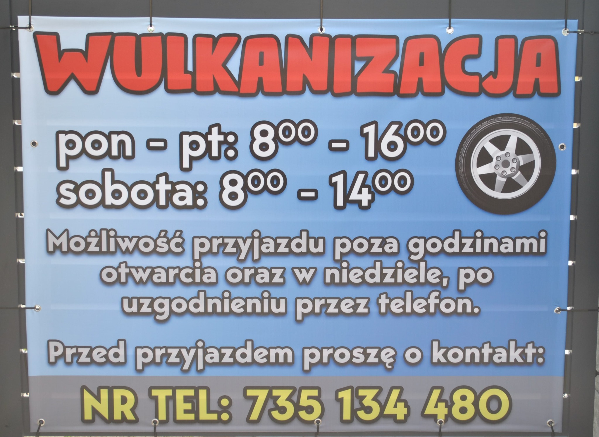 Baner reklamowy z napisem 'Wulkanizacja', godzinami otwarcia i numerem telefonu, ozdobiony grafiką opony z felgą