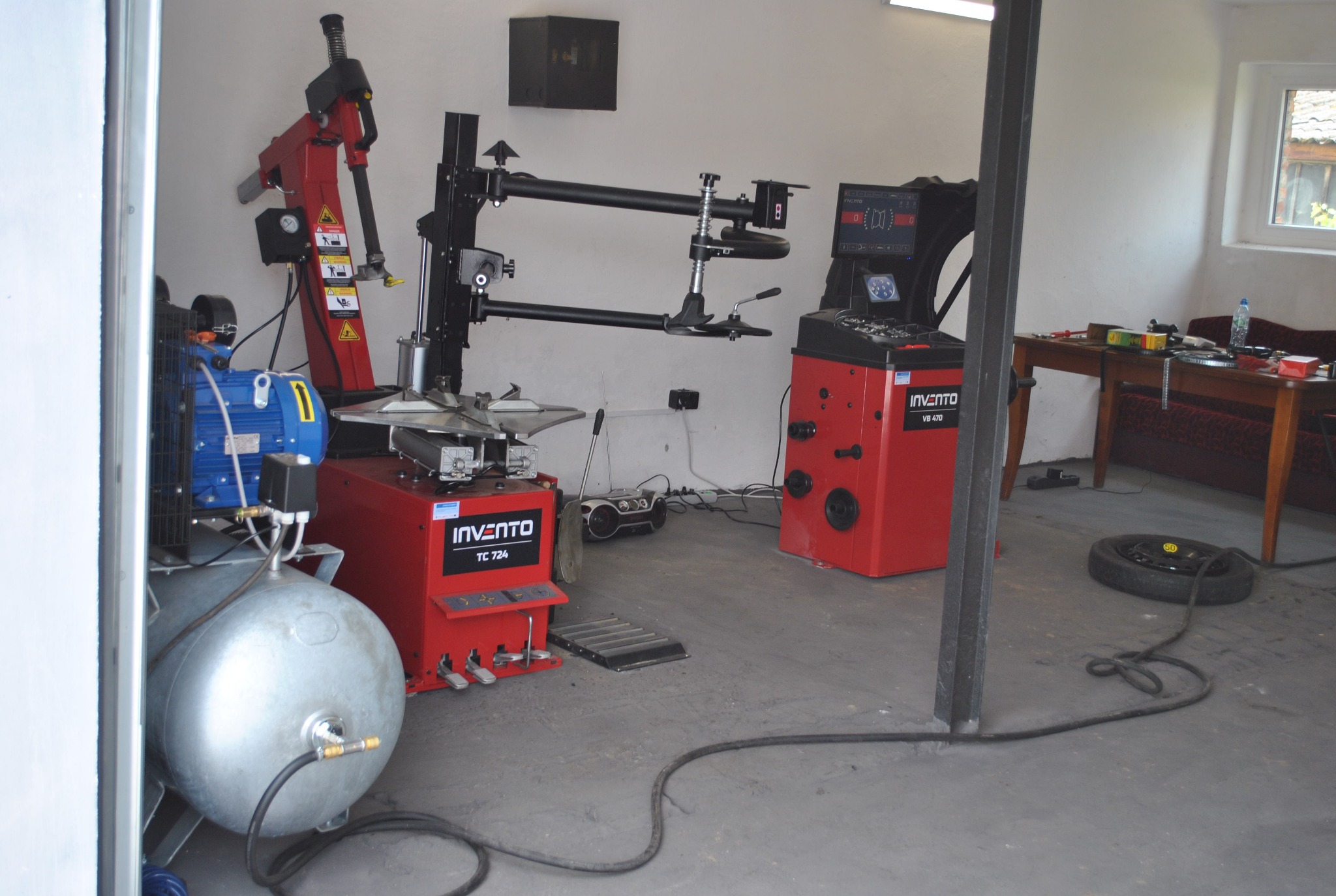 Wyposażenie warsztatu samochodowego: montażownica do opon i wyważarka kół marki Invento, widoczne przewody pneumatyczne na betonowej posadzce.