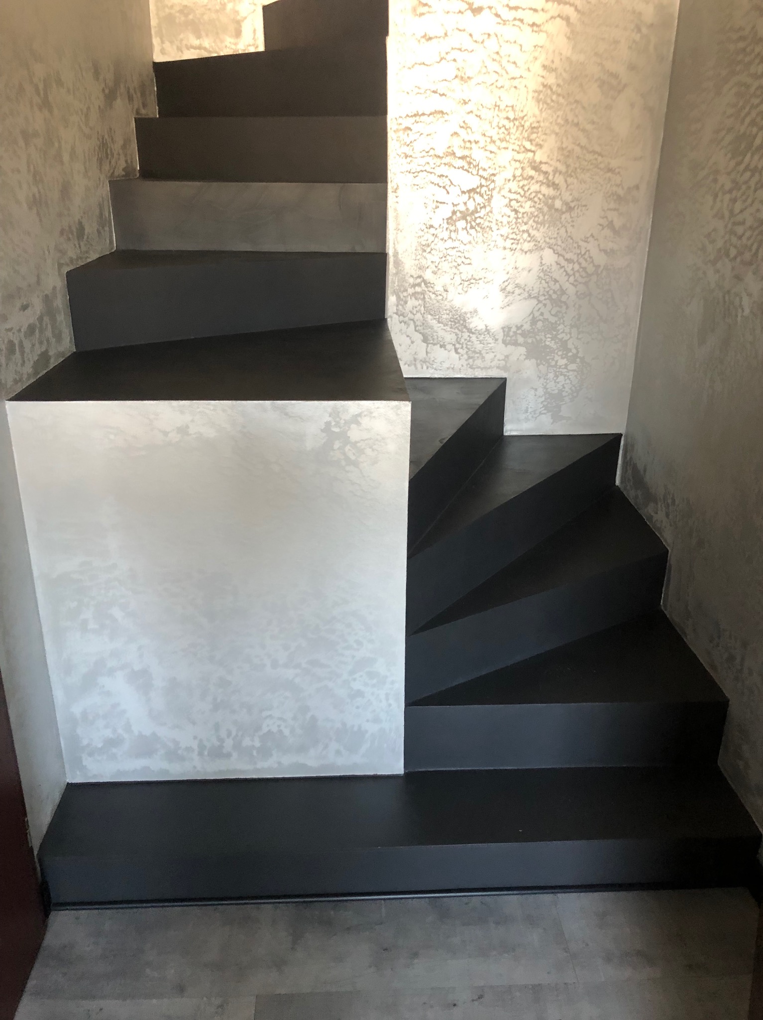 Schody wewnętrzne wykończone czarną farbą, ściany pokryte dekoracyjną, srebrzystą fakturą przypominającą chmury.