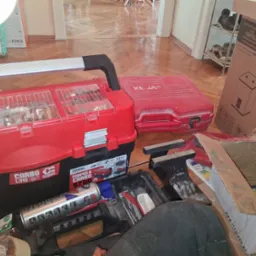 Skrzynka narzędziowa Patrol Carbo 5700 i pudełko z grzejnikiem Napoli 15L na podłodze w Bielsku-Białej. Widoczne narzędzia i akcesoria instalacyjne.