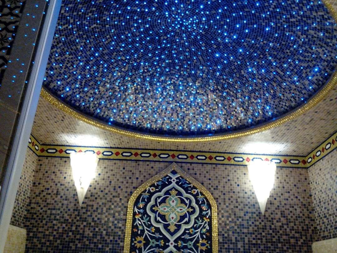 Mozaikowy sufit kopułowy z efektem gwieździstego nieba i dekoracyjnym oświetleniem ściennym w orientalnym stylu.