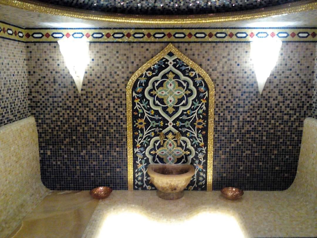 Mozaika w orientalnym stylu w łazience, z dekoracyjnym panelem nad umywalką i podświetlanymi niszami w ścianie.