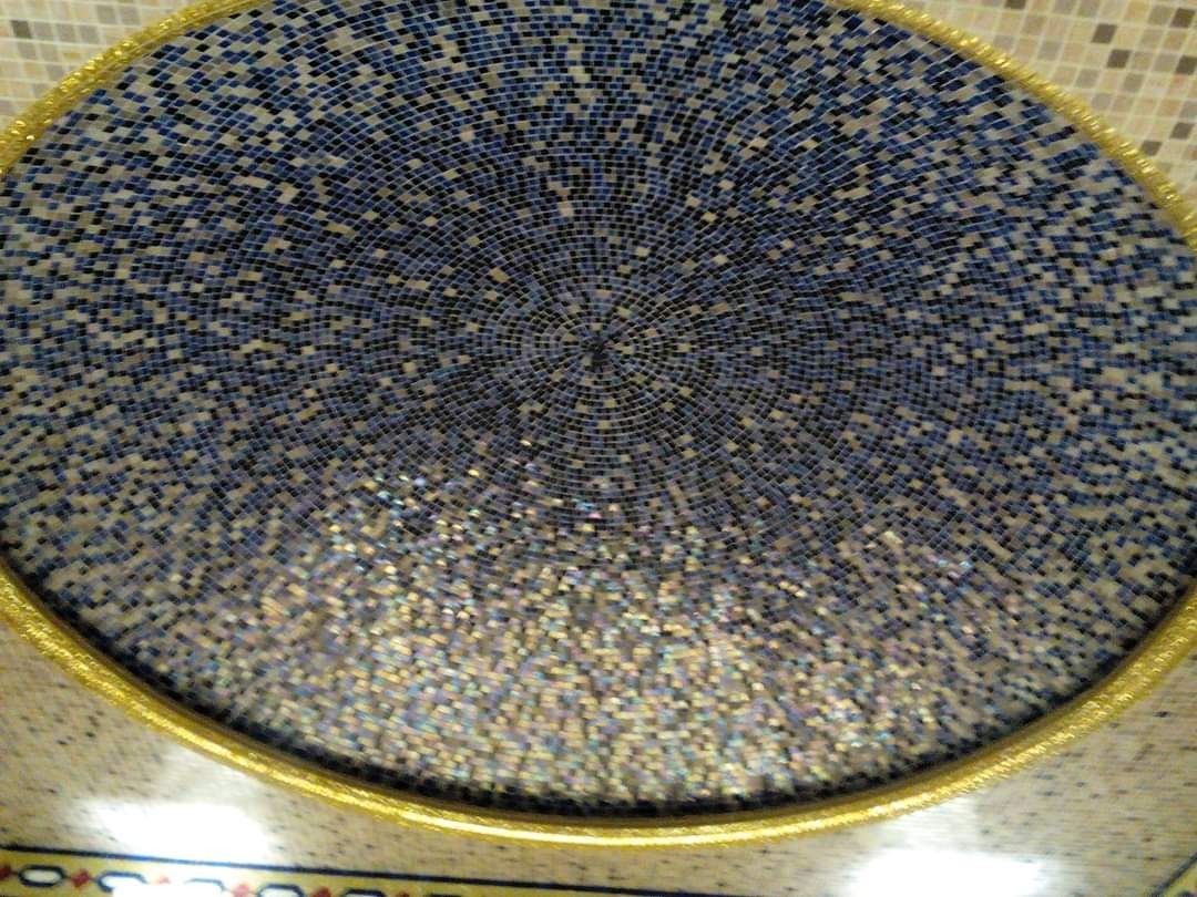 Dekoracyjny sufit z mozaiki w odcieniach błękitu, bieli i złota, ułożony w koncentryczny wzór.