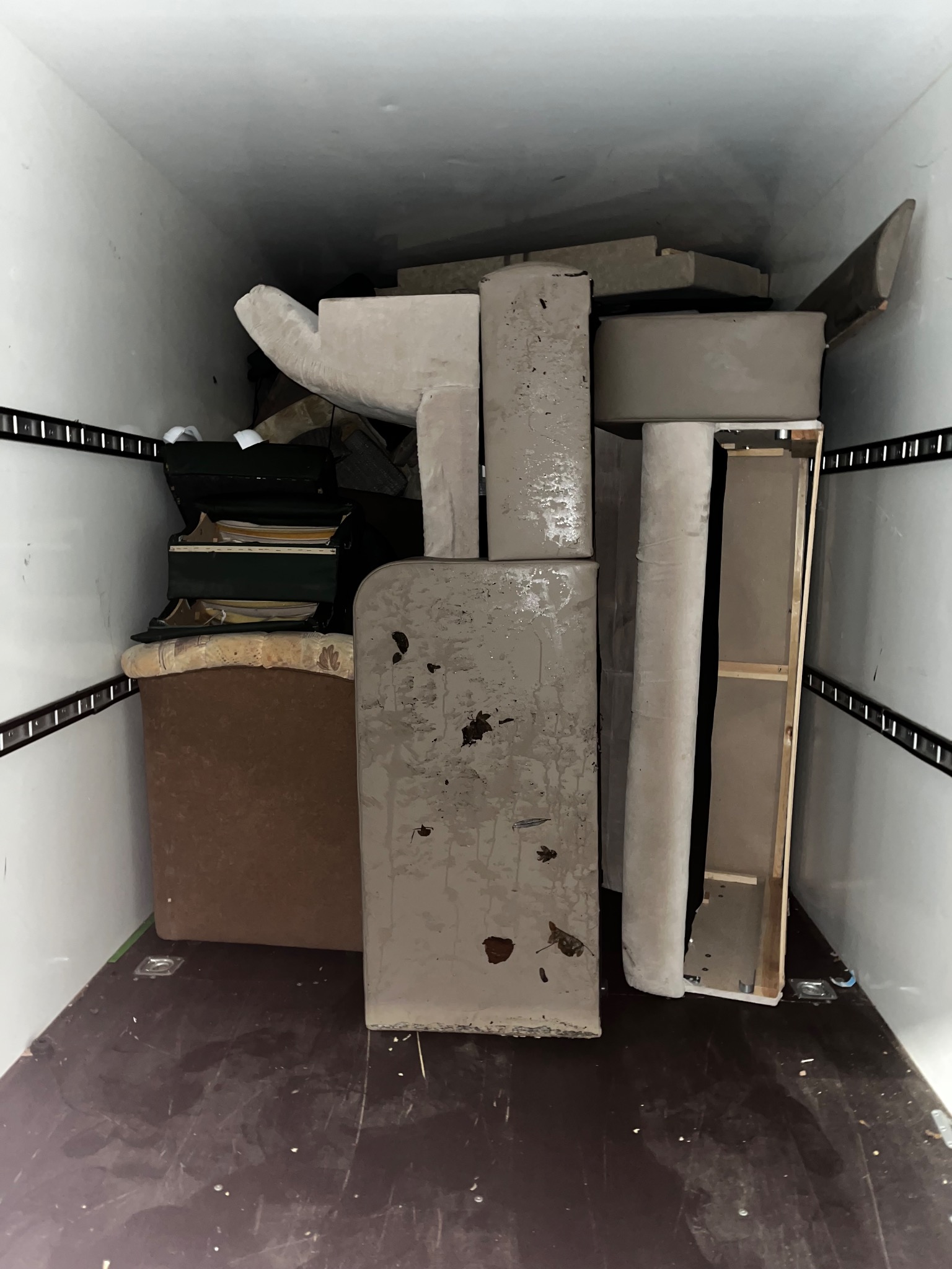 Częściowo zdemontowane meble, w tym krzesła i elementy tapicerowane, przewożone wewnątrz furgonetki transportowej.