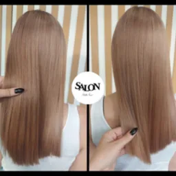 Proste, lśniące włosy w odcieniu chłodnego blondu, widok z tyłu, z logo salonu w centralnej części kadru i dłonią z czarnym manicure sprawdzającą gładkość włosów.