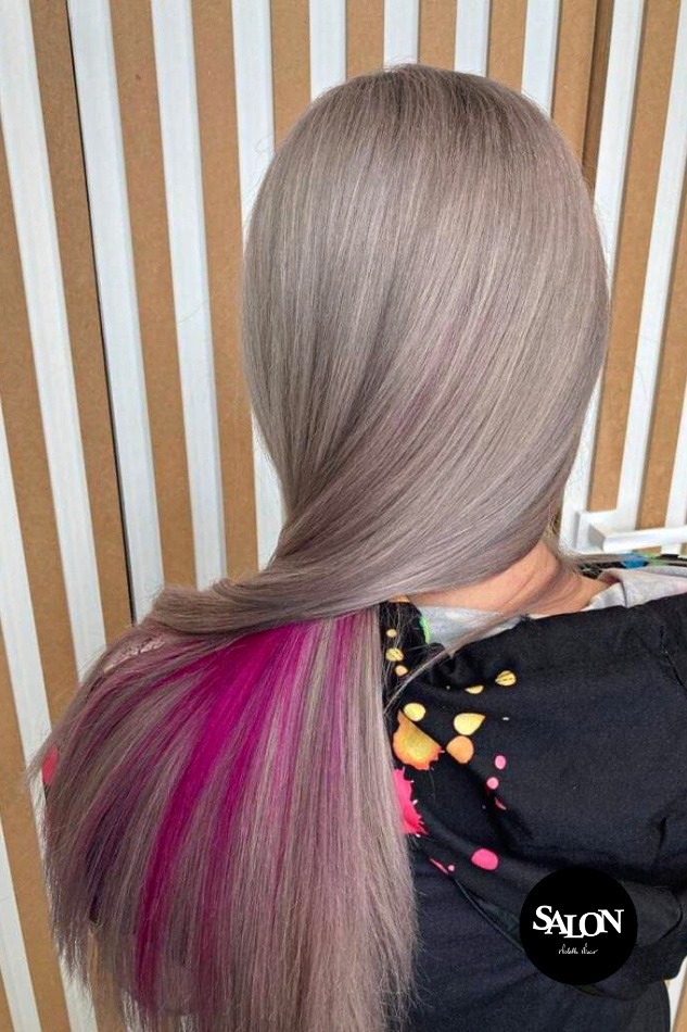 Popielate włosy z różowymi pasemkami, widok z tyłu, na tle ściany z pionowymi paskami.