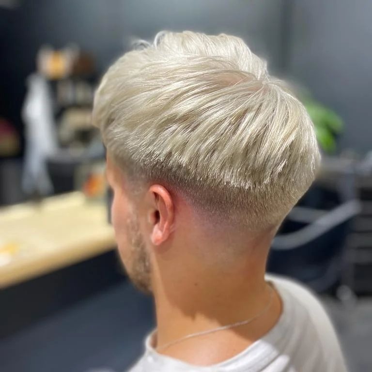 Męska fryzura: platynowy blond z cieniowaniem, widok z tyłu, delikatny zarost na karku.