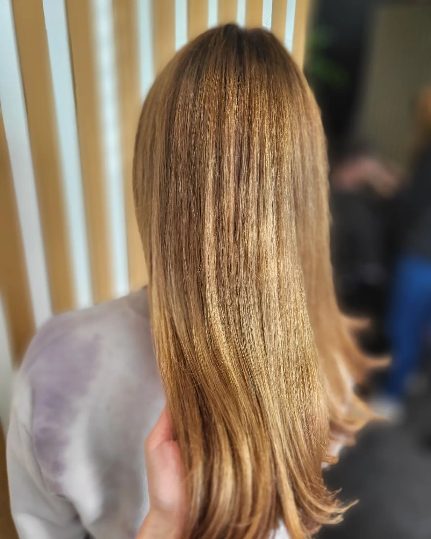 Świeżo ufarbowane, lśniące włosy w odcieniach blondu i brązu, widok z tyłu, delikatne fale na końcach.