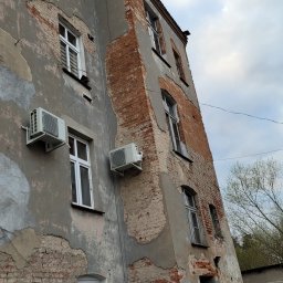 AClimacik Chłodnictwo Klimatyzacja - Zewnętrzne jednostki klimatyzacji zamontowane na elewacji starego, częściowo odrestaurowanego budynku z odsłoniętą cegłą i widocznymi śladami napraw.