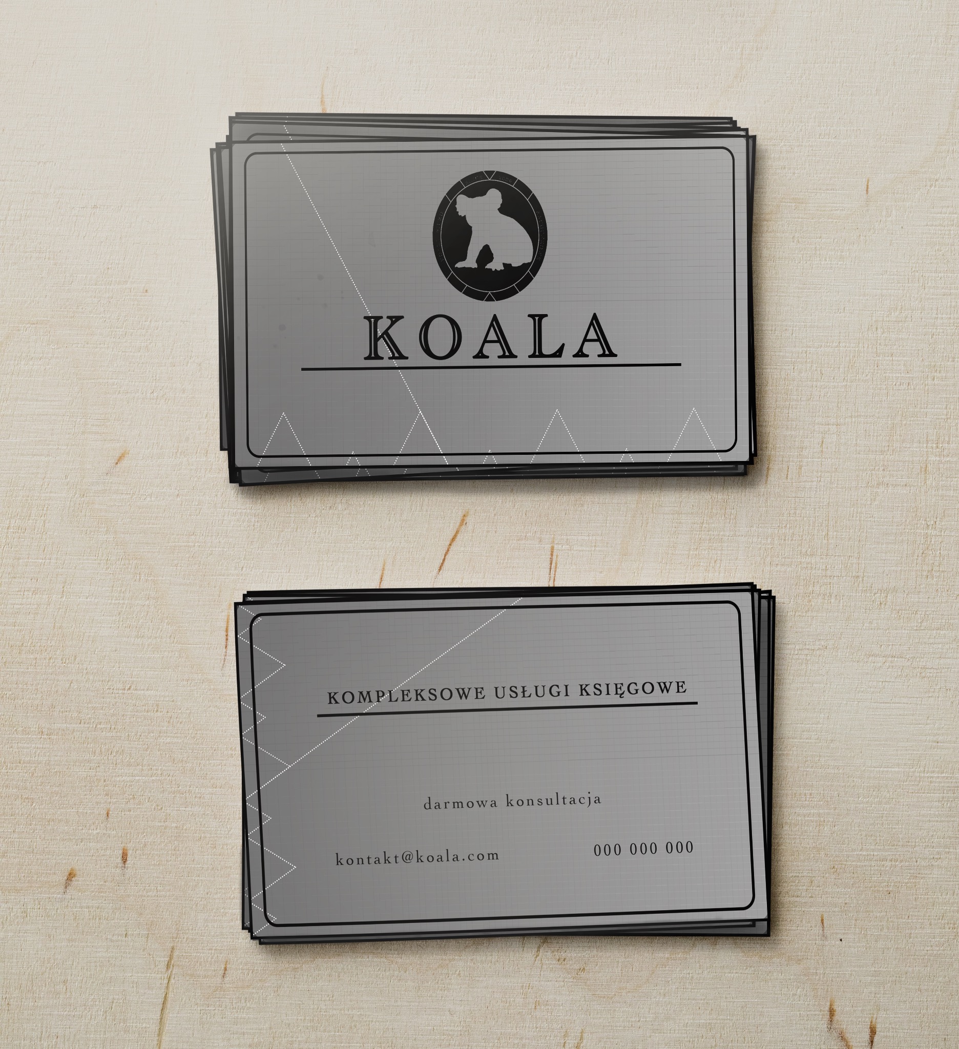Stos wizytówek z logo firmy Koala oferującej kompleksowe usługi księgowe i darmową konsultację, na teksturowanym drewnianym tle.
