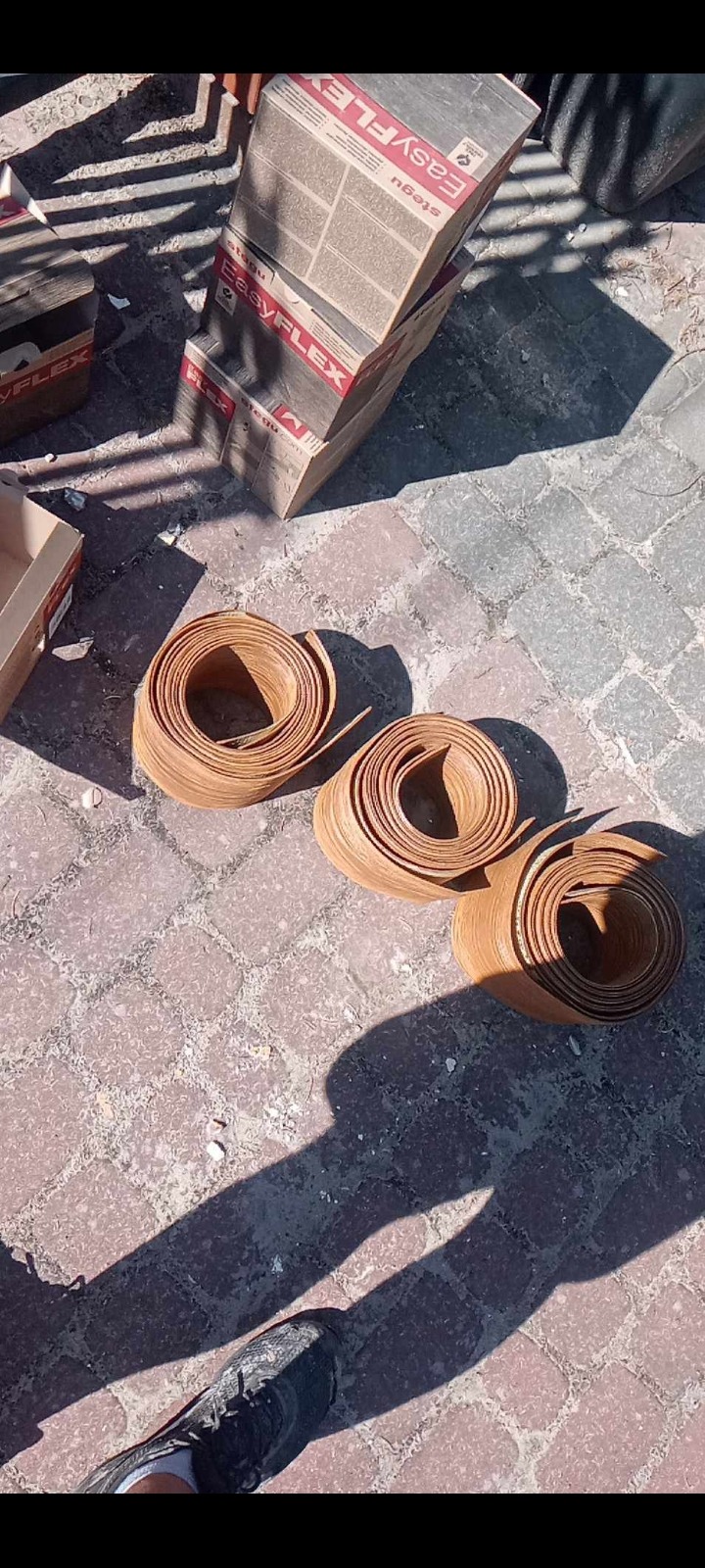Rolki forniru i opakowania płytek elastycznych Stegu Easy Flex na brukowanej powierzchni w Bydgoszczy, rzucające wyraźny cień.