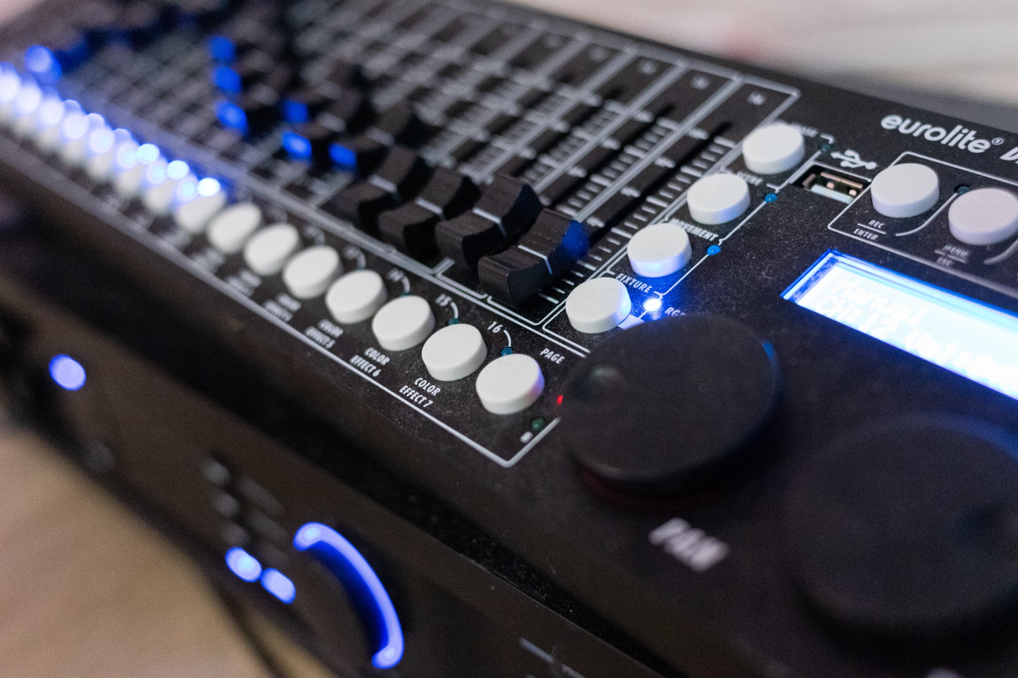 Panel sterowania oświetleniem Eurolite DMX z suwakami, przyciskami i wyświetlaczem, podświetlony niebieskimi diodami LED.