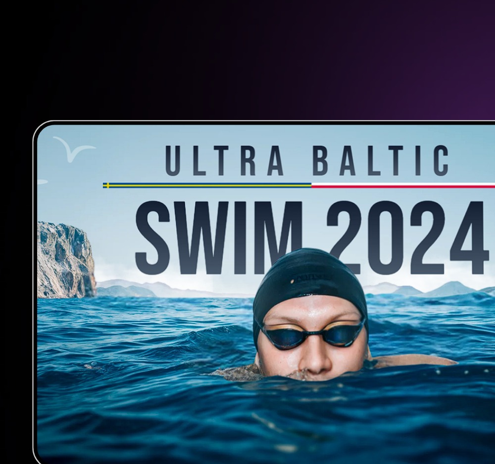 Mężczyzna w czepku i okularach pływackich podczas Ultra Baltic Swim 2024, z widocznymi falami i skalistym brzegiem w tle.