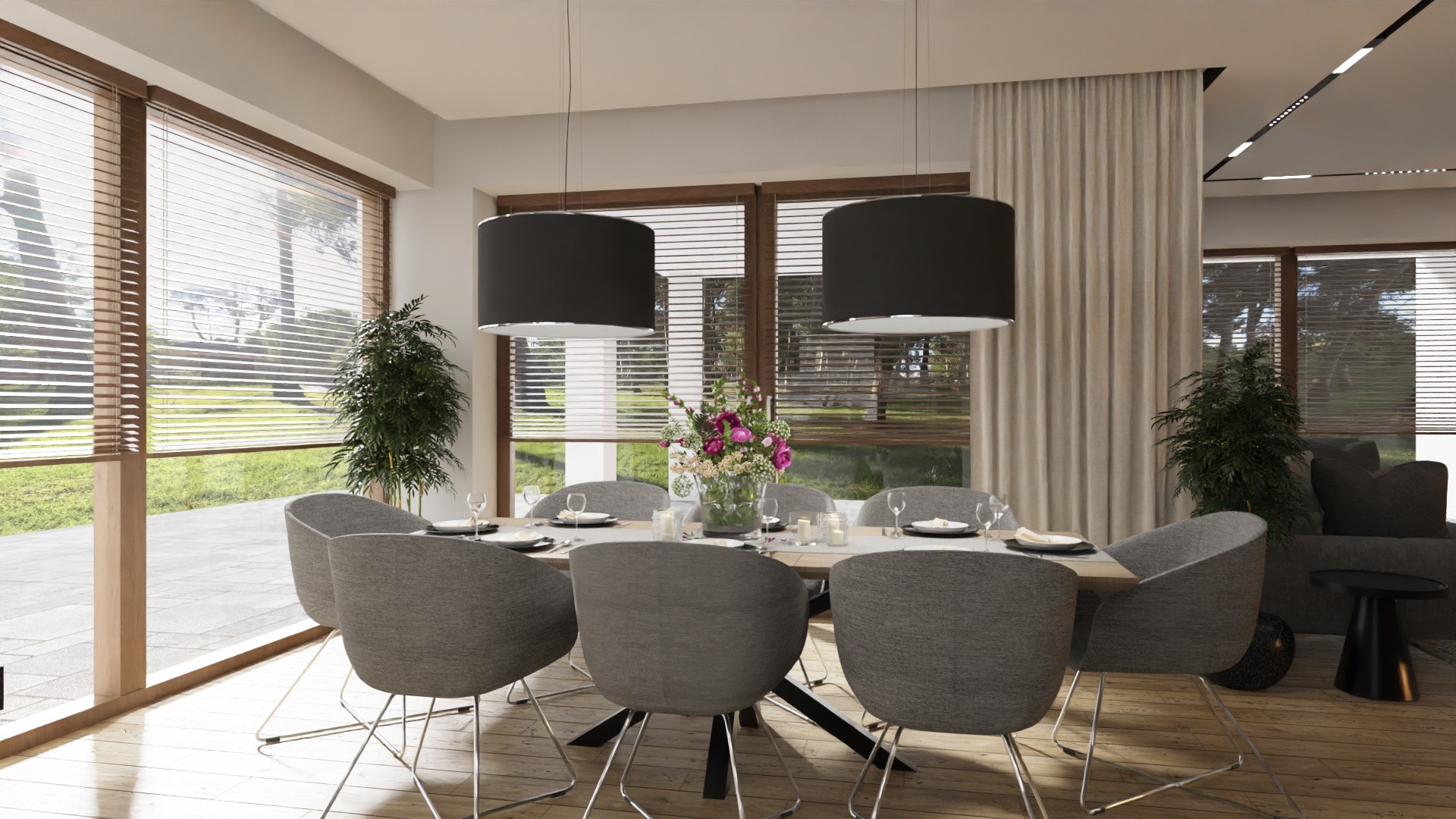 Jasna jadalnia z drewnianą podłogą, stołem z szarymi krzesłami, dwoma czarnymi lampami wiszącymi i widokiem na ogród przez okna z żaluzjami.