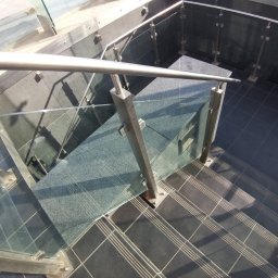 GSM SPOLKA Z OGRANICZONA ODPOWIEDZIALNOSCIA - Nowoczesne schody z czarnych płytek z metalową balustradą i szklanymi panelami, widok z góry.