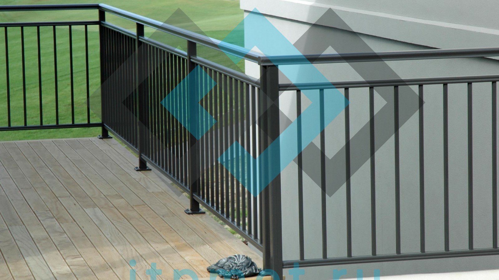 Metalowa balustrada z pionowymi szczeblami, zamontowana na drewnianym tarasie z widokiem na trawnik, z dekoracyjną figurką żółwia u podstawy jednego ze słupków.