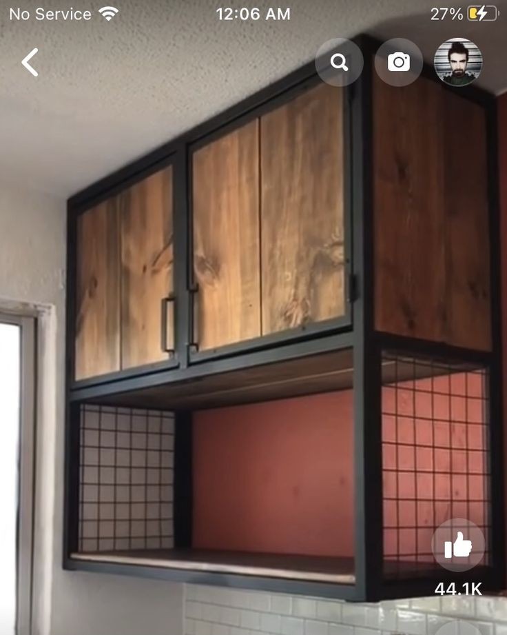 Rustykalne szafki kuchenne z drewnianymi frontami i metalową ramą, otwarte półki z siatki drucianej poniżej, widok z dołu, jasne oświetlenie.