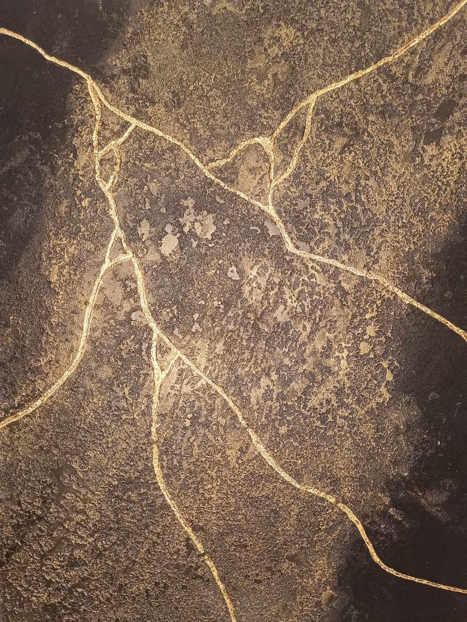 Dekoracyjna ściana z ciemną, chropowatą fakturą i złotymi, nieregularnymi żyłkami imitującymi spękania, przypominająca technikę Kintsugi.