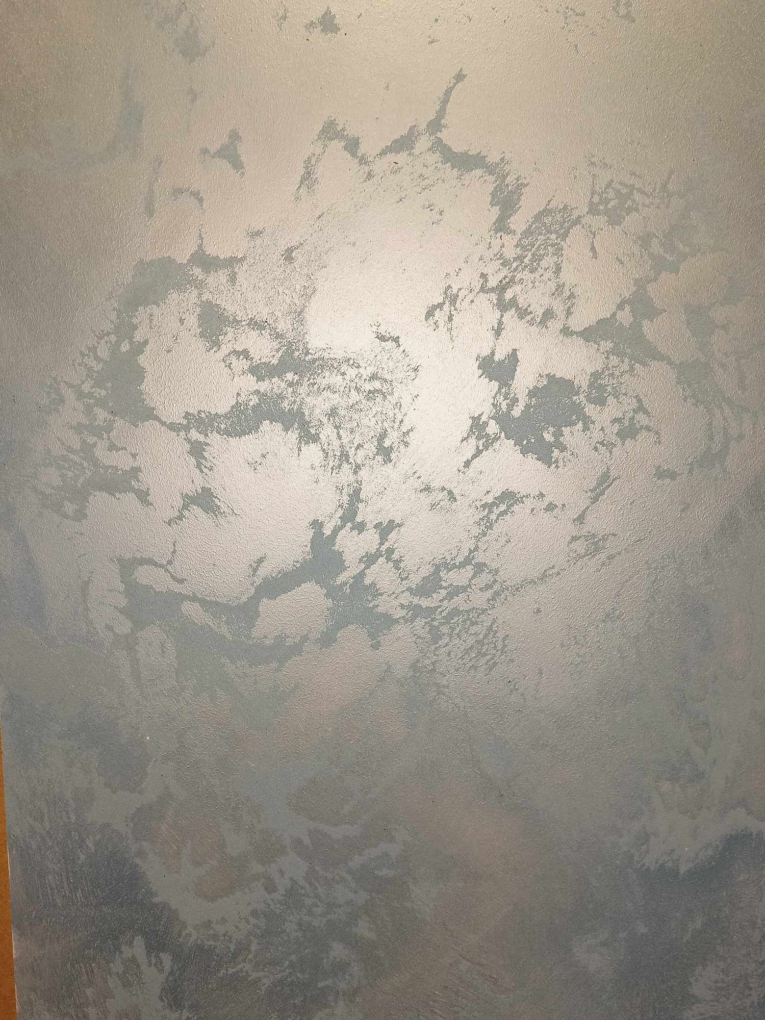 Ściana z efektem dekoracyjnym w odcieniach szarości i srebra, przypominającym chmury lub marmur, z delikatną teksturą i połyskiem.