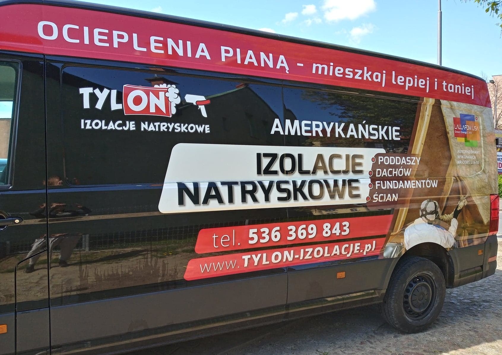 Czarny samochód dostawczy z reklamą firmy Tylon oferującej amerykańskie izolacje natryskowe poddaszy, dachów, fundamentów i ścian, z numerem telefonu i adresem strony internetowej.