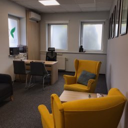 Centrum Psychiatrii i Psychoterapii COLLIGO w Bydgoszczy - Jasne wnętrze gabinetu z żółtymi fotelami typu uszak, biurkiem z komputerem i szarą wykładziną. Na parapecie okna siedzi mała figurka małpki.